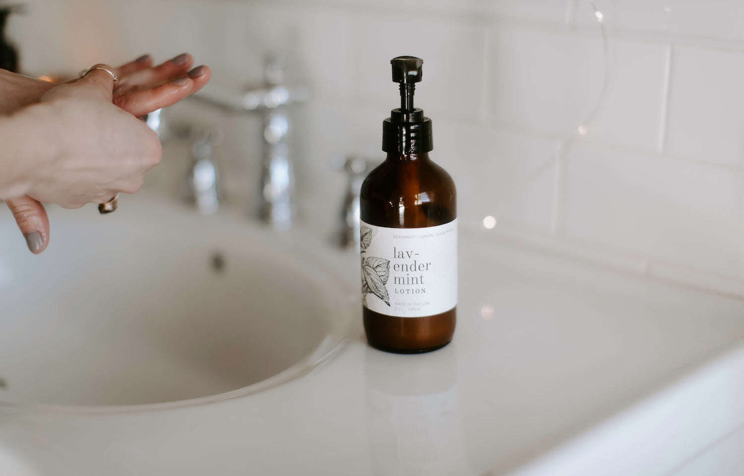 8oz Lavender Mint Body Lotion on a bathroom counter next to the sink. 