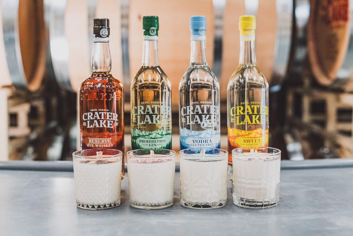 4 Prohibition Soy Candles in front of liquor bottles from Crater Lake Distilling. 