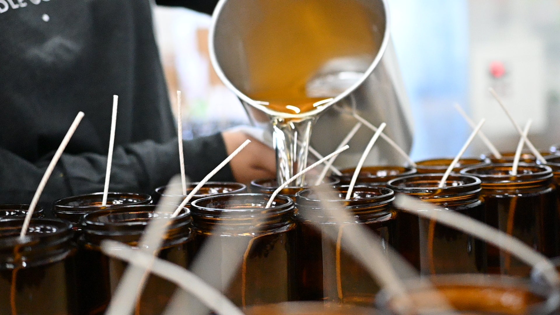 9oz jar candles being filled with wax by hand. 