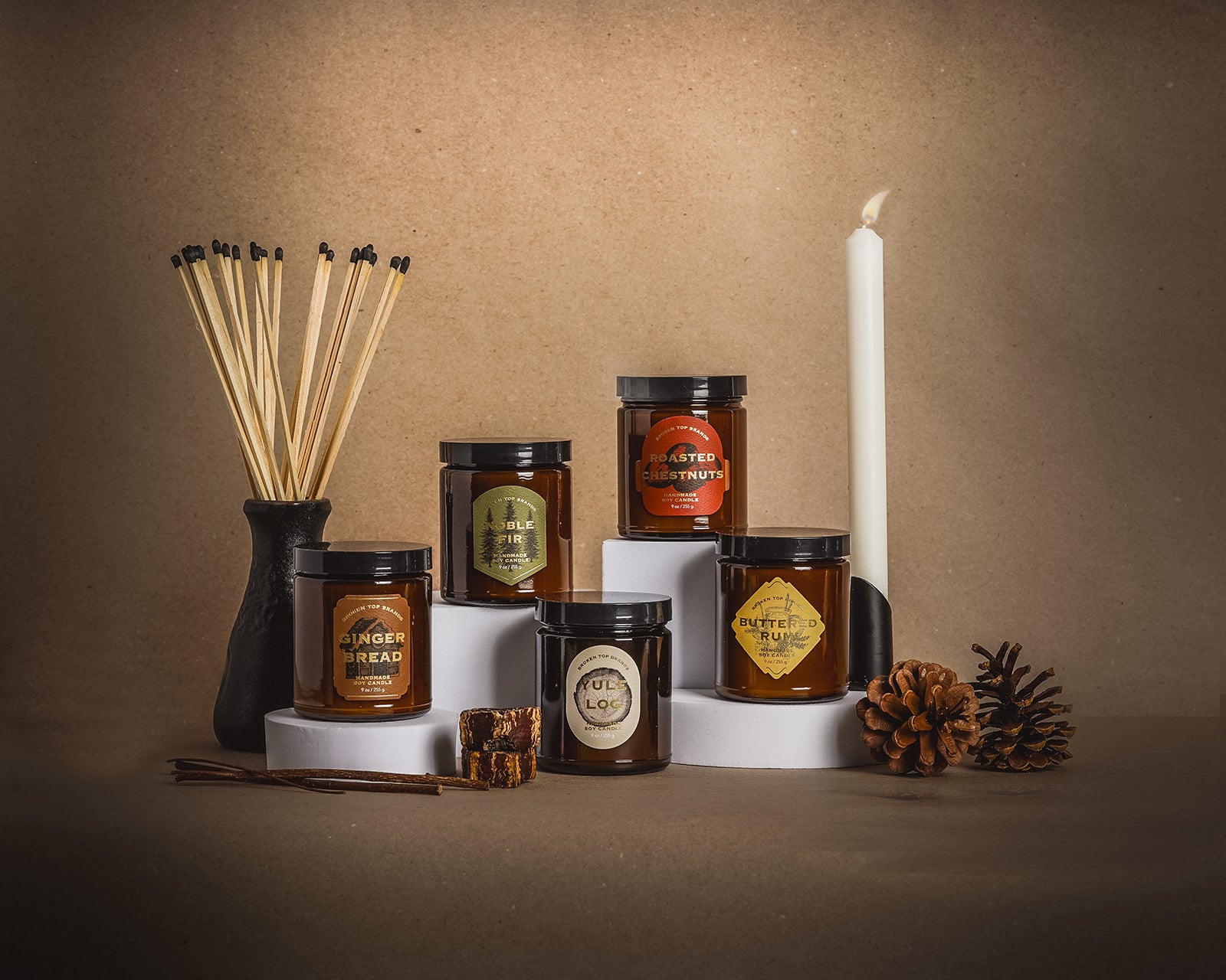 Holiday Heritage Soy Candle Collection by Broken Top Brands. 9oz Gingerbread Soy Candle, 9oz Noble Fir Soy Candle, 9oz Buttered Rum Soy Candle, 9oz Roasted Chestnut Soy Candle, and 9oz Yule Log Soy Candle. 