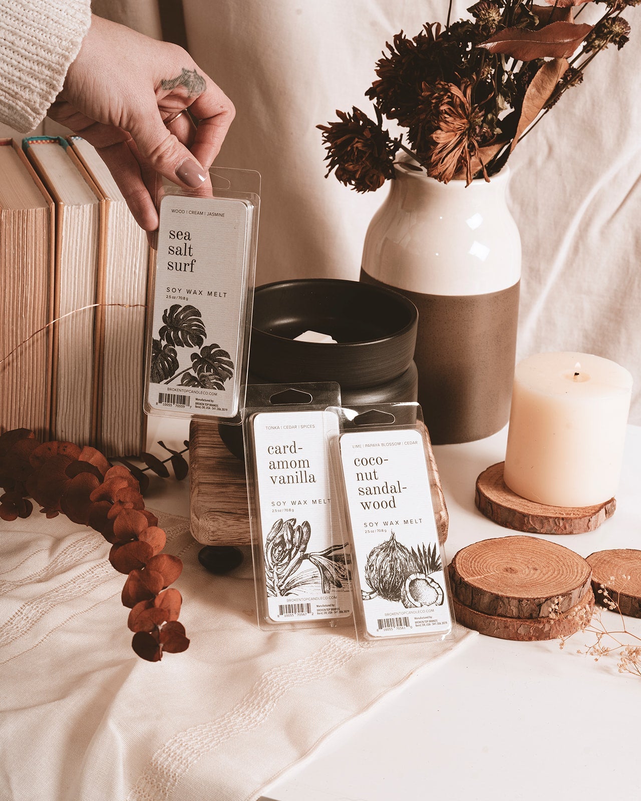 Sea Salt Surf, Cardamom Vanilla, and Coconut Sandalwood Soy Wax Melts in font of a black wax melter. 