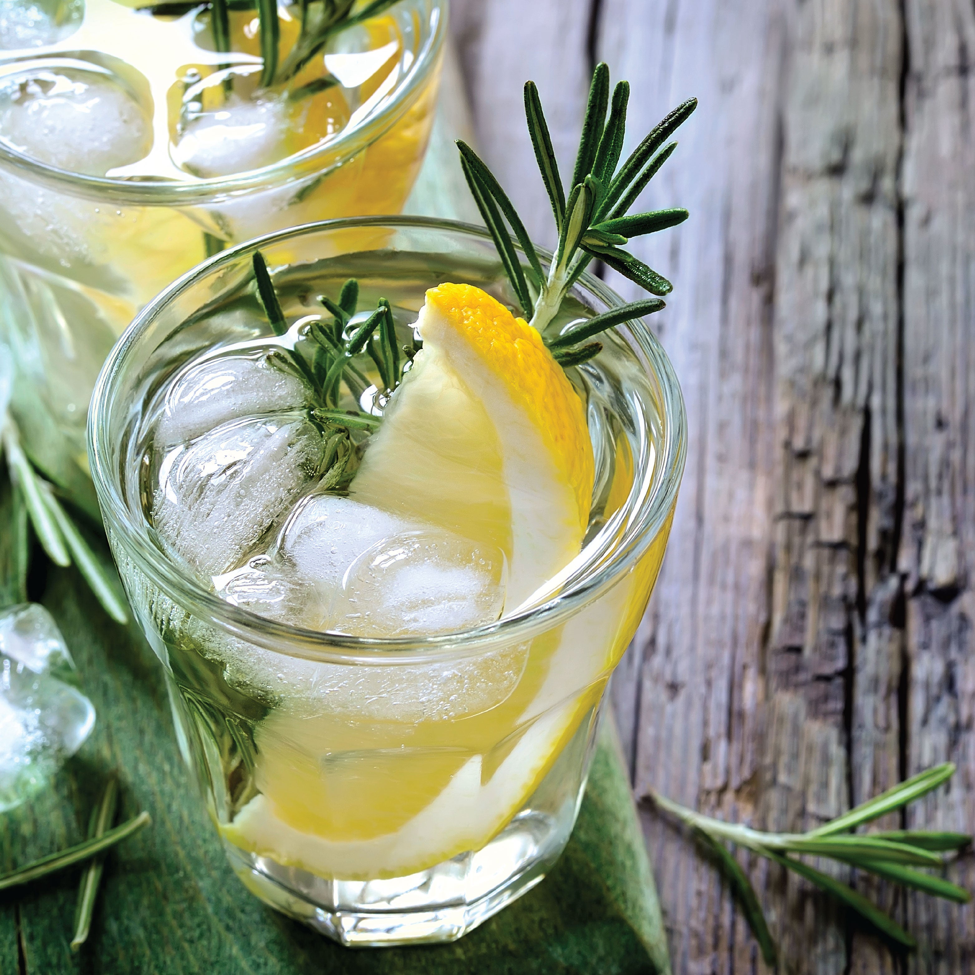A cocktail with a lemon and rosemary garnish.