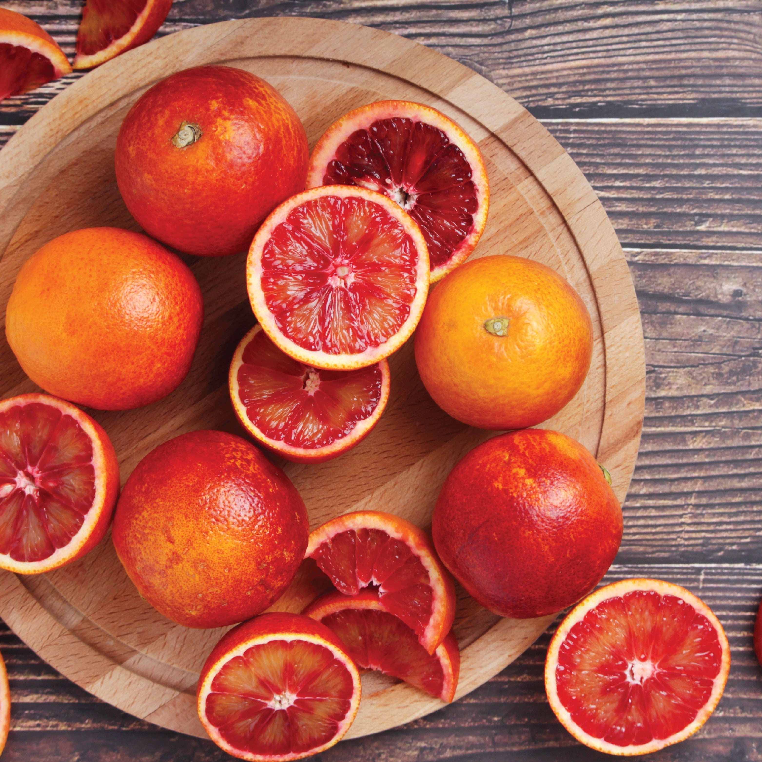 Sliced blood oranges on a wooden cutting board.