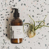 8oz Saguaro Cactus Body Lotion on a speckled countertop next to a small decorative plant. 