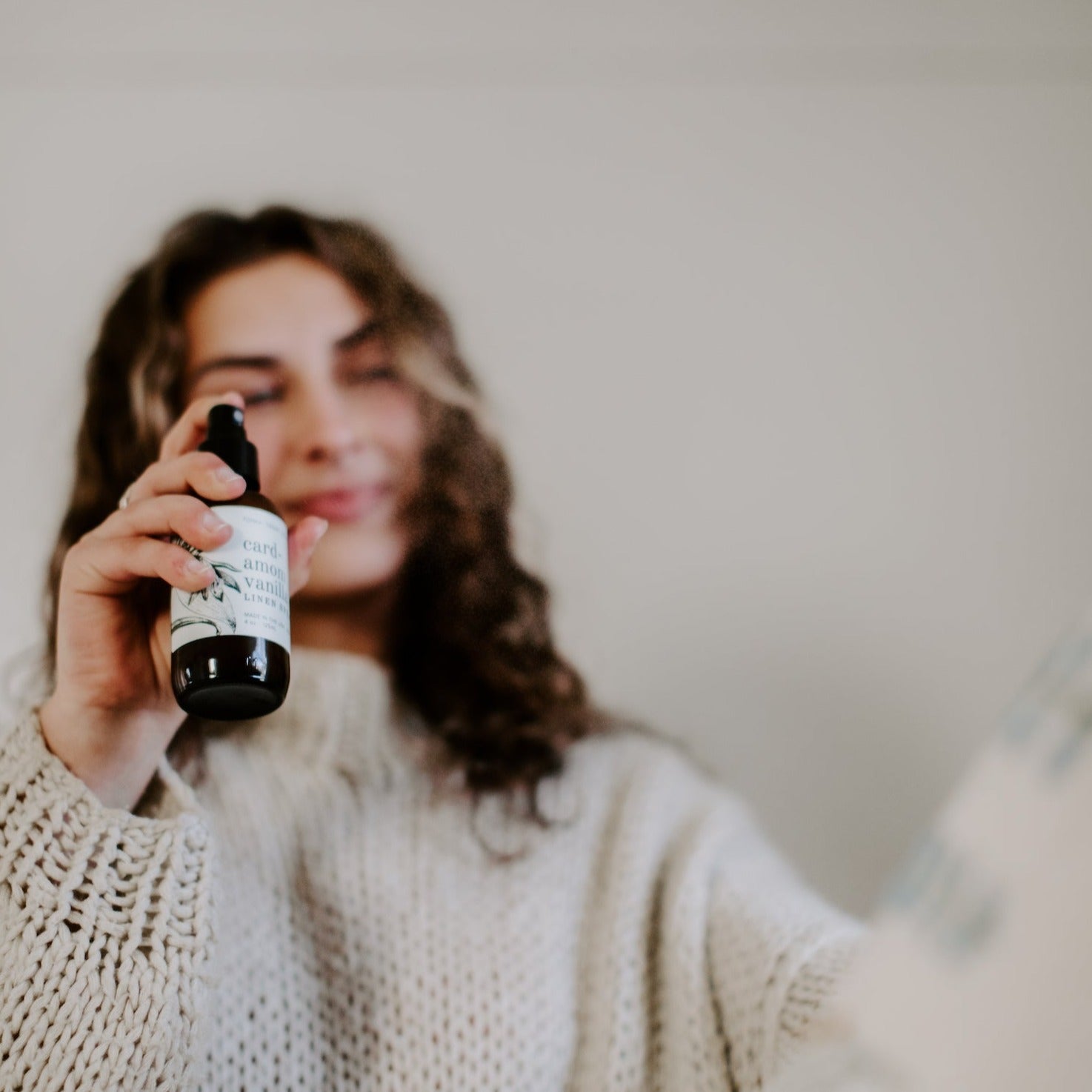 4oz Cardamom Vanilla Linen Spray being sprayed by a woman. 