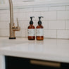 8oz Cardamom Vanilla Liquid Soap and 8oz Cardamom Vanilla Body Lotion next to a kitchen sink. 