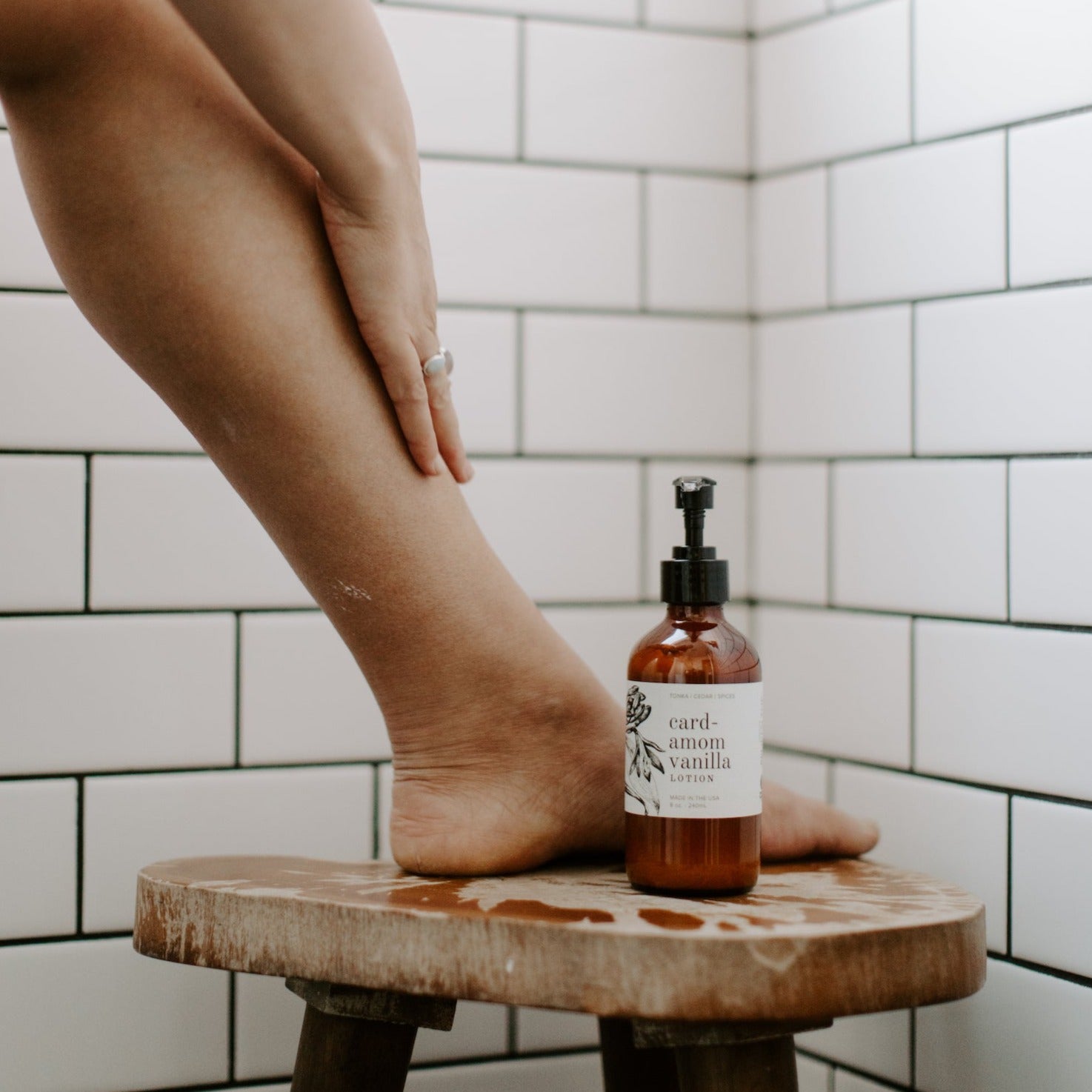 8oz Cardamom Vanilla Body Lotion on a wooden stool with a leg. 