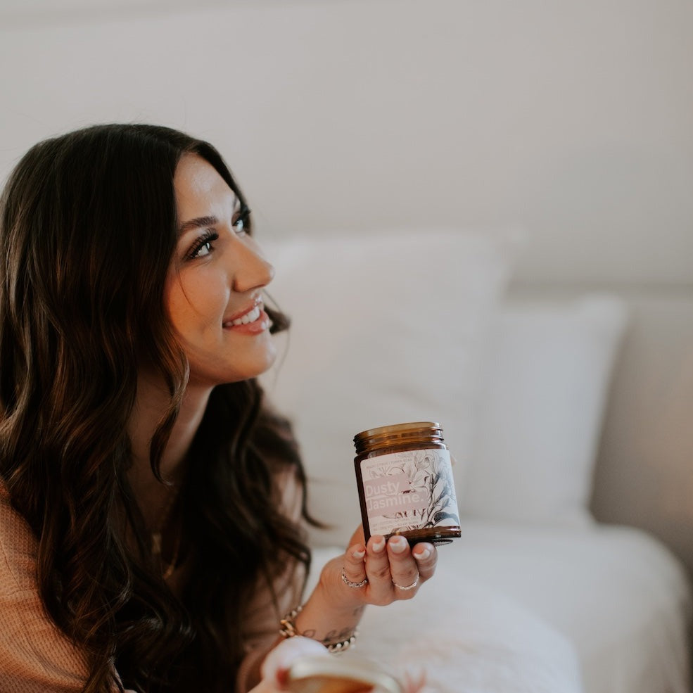 9oz Dusty Jasmine Soy Candle being held by a woman. 