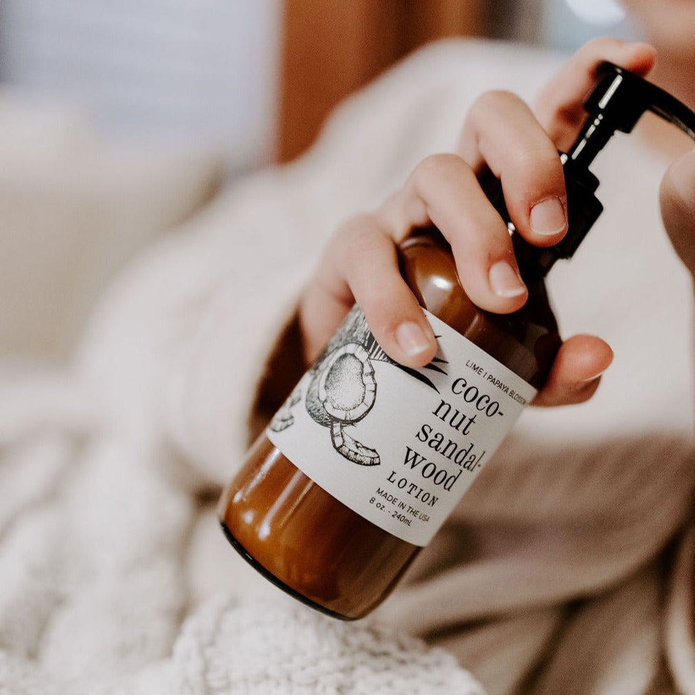8oz Coconut Sandalwood Body Lotion being dispensed by one hand. 