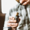 1oz Black Coral Tide Beard Oil being held by two hands. 
