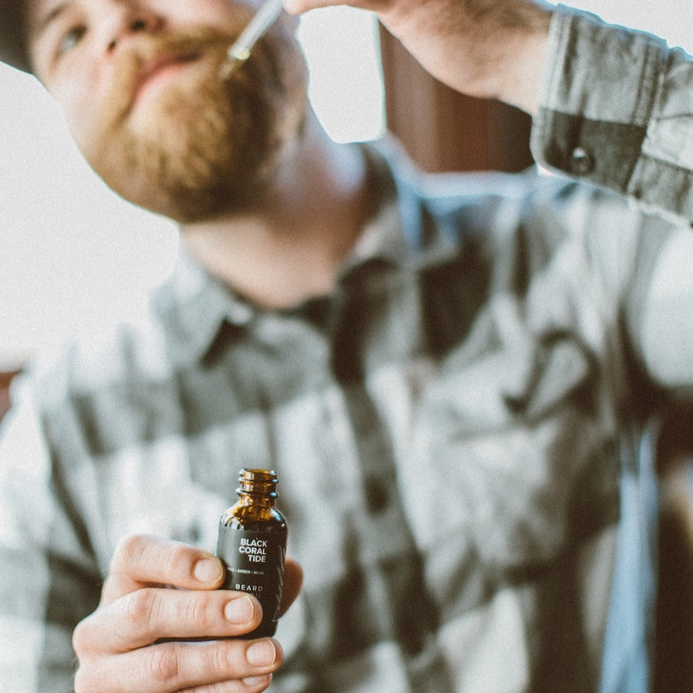 1oz Black Coral Tide Beard Oil being applied by man with beard. 