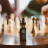 1oz Sitka Woodland Beard Oil on a table with a chess board in the background. 