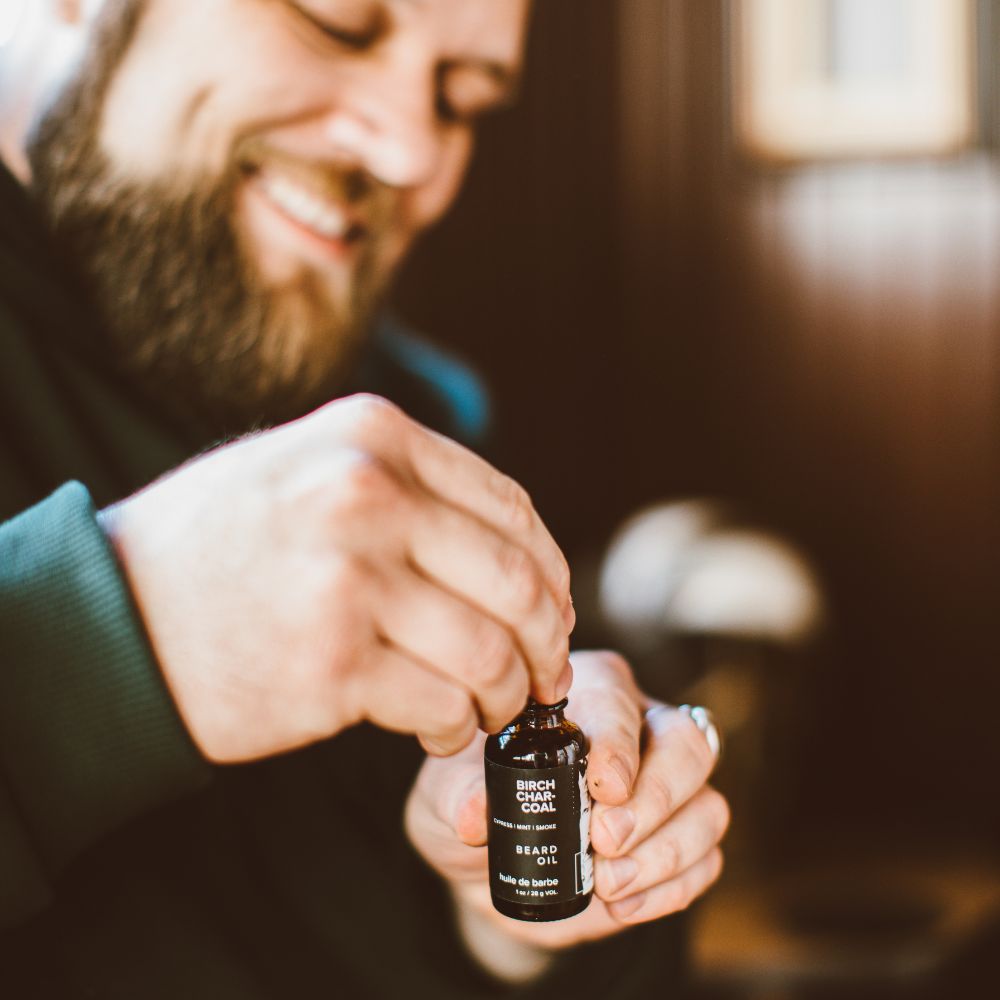 Birch Charcoal Beard Oil being opened by a bearded man. 