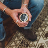 Birch Charcoal Solid Cologne being held by two hands.