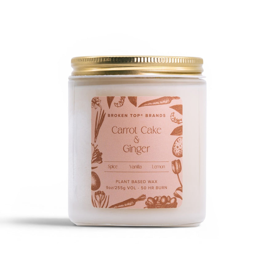 Candle jar labeled 'Carrot Cake & Ginger' with a gold lid on a white background