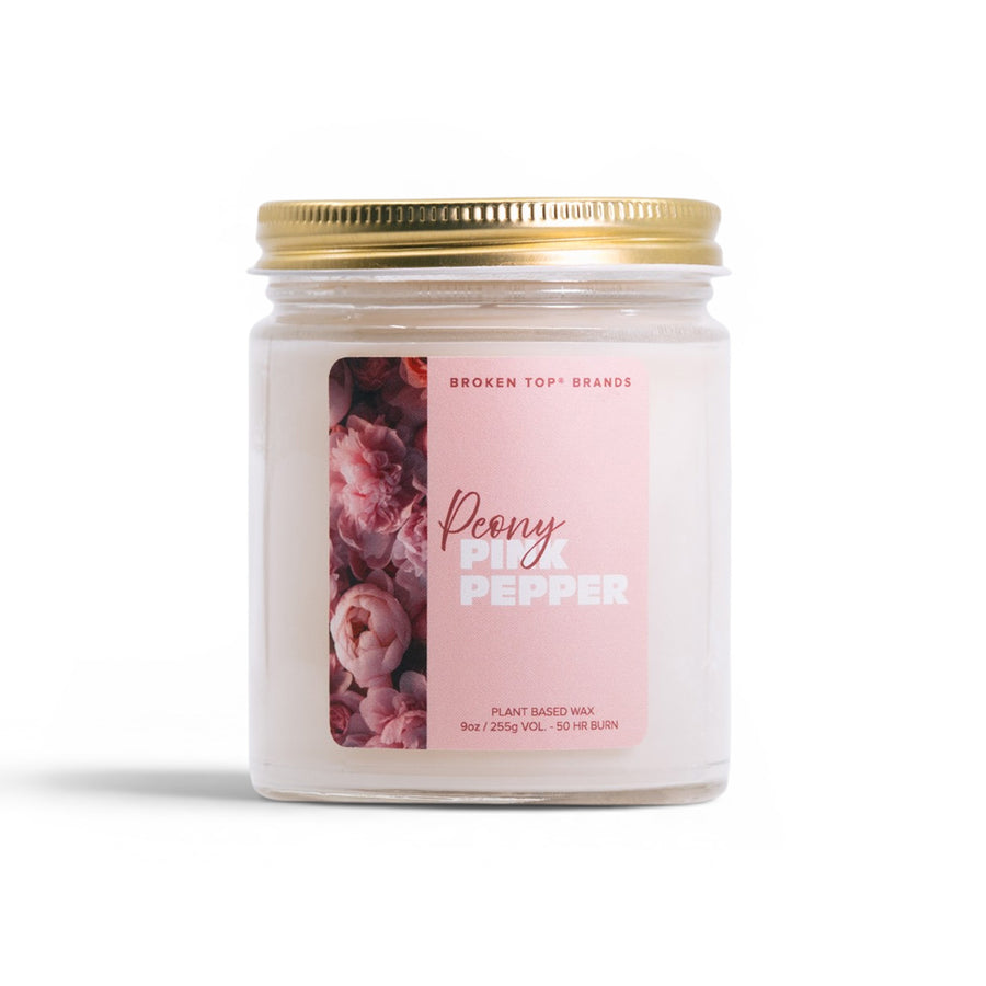 Candle jar labeled 'Peony Pink Pepper' with a gold lid on a white background