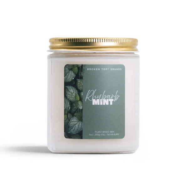 Candle jar with gold lid and green label on a white background