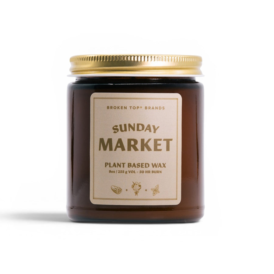 Candle jar with a gold lid and 'Sunday Market' label on a white background