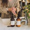 Apricot Bloom 8oz Liquid Soap and 8oz Apricot Bloom Body Lotion in front of a kitchen sink with a woman washing her hands. 