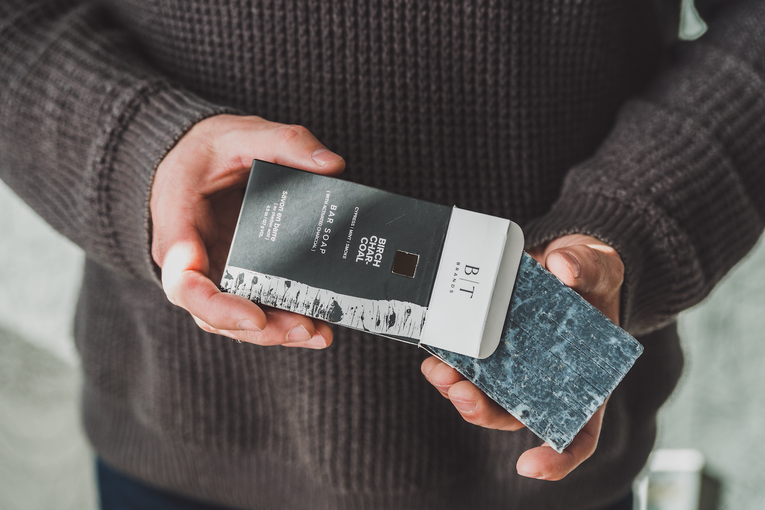 Birch Charcoal Bar Soap being removed from the box by a man's hands. 