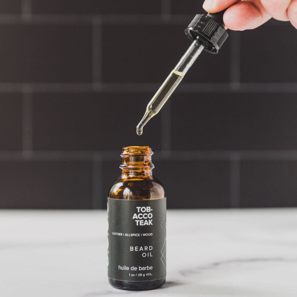 1oz Tobacco Teak Beard Oil on a countertop with dropper in use. 