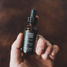 1oz Birch Charcoal Beard Oil being held by a hand. 