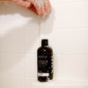 16oz Birch Charcoal Body Wash in white tiled shower. 