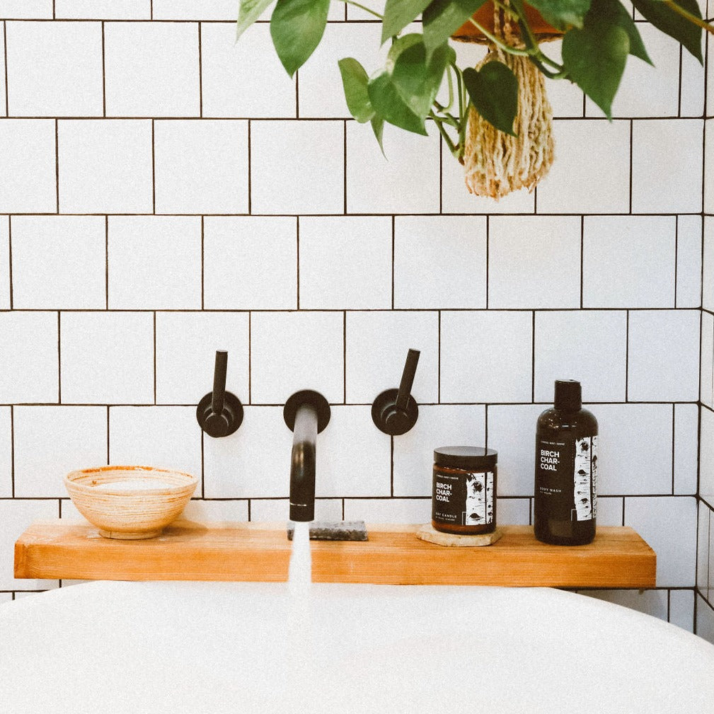 16oz Birch Charcoal Body Wash on bathtub with 9oz Birch Charcoal Soy Candle. 
