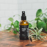 4oz Black Coral Tide Man Spray next to decorative plants. 