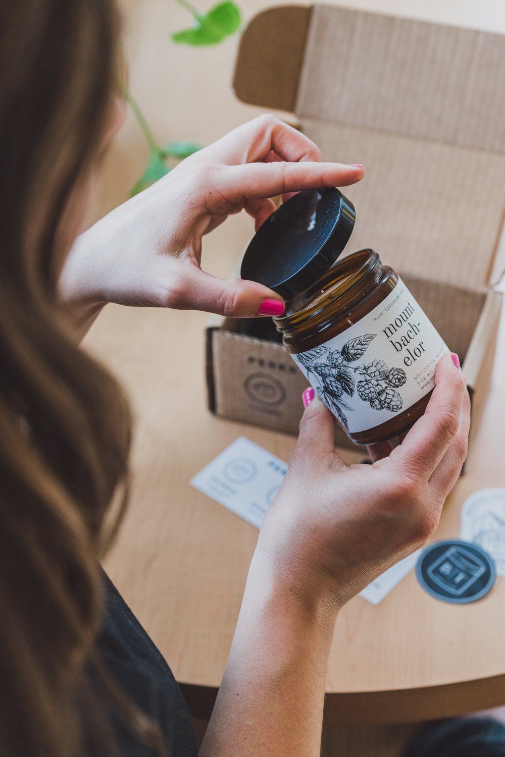 9oz Mount Bachelor Soy Candle being opened by a woman. 