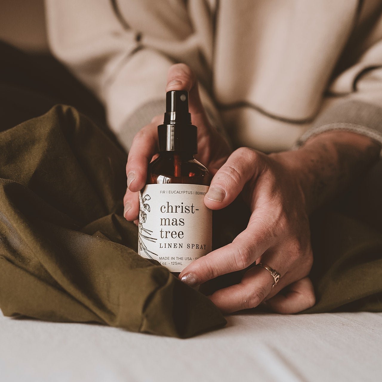 4oz Christmas Tree Linen Spray being held by two hands. 