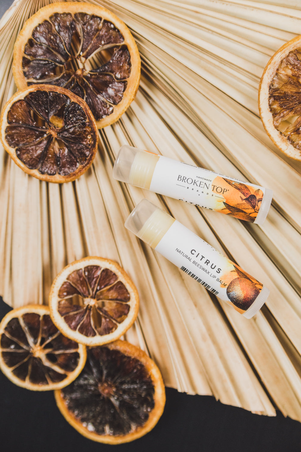 Two Citrus Lip Balms next to decorative dried citrus slices. 