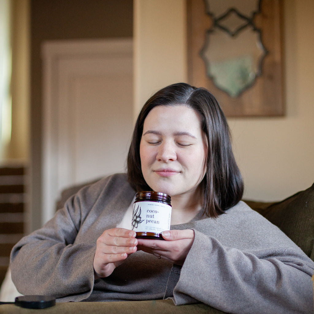 9oz Coconut Pecan Soy Candle being smelled by a woman. 