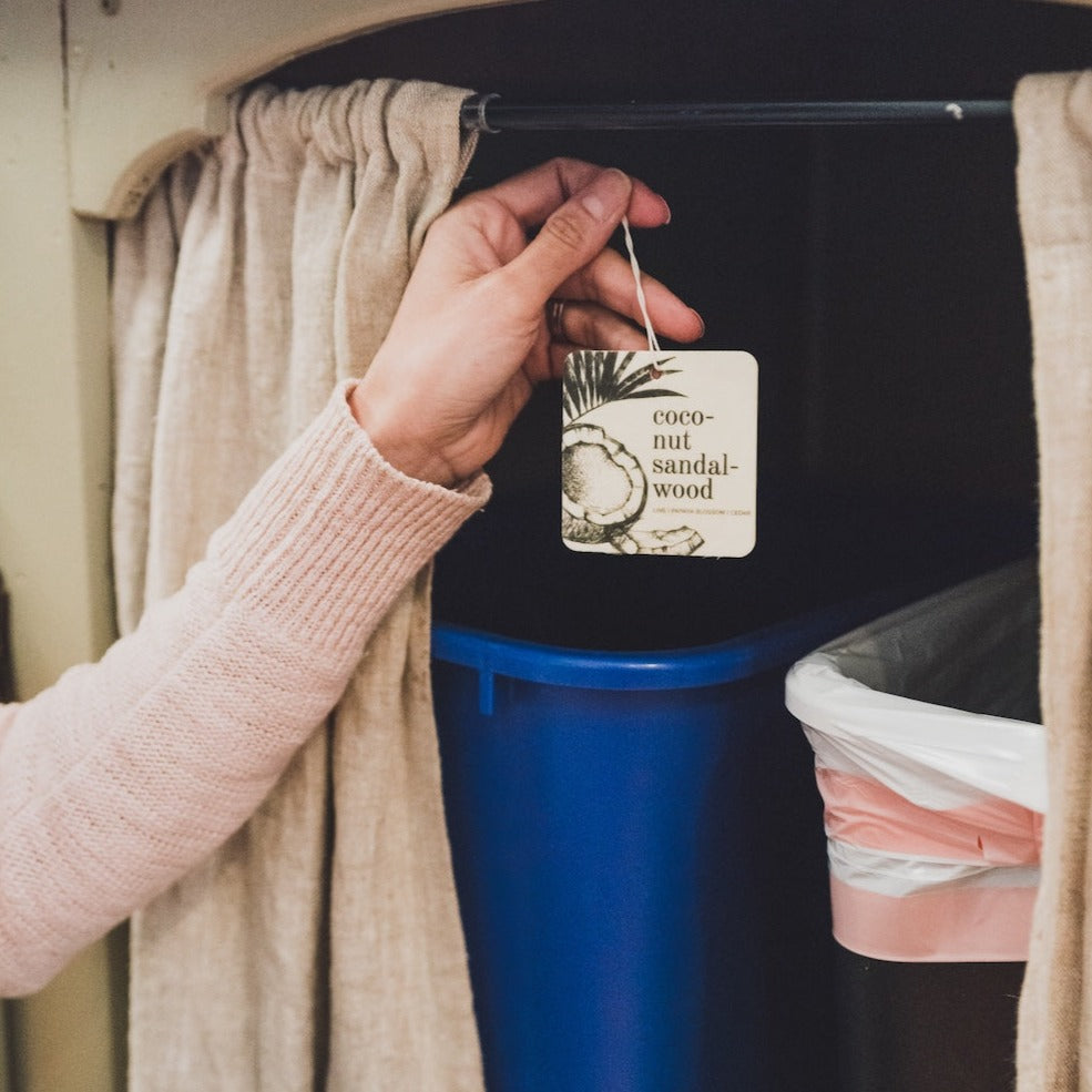 Coconut Sandalwood Car Freshener being placed above garbage cans. 