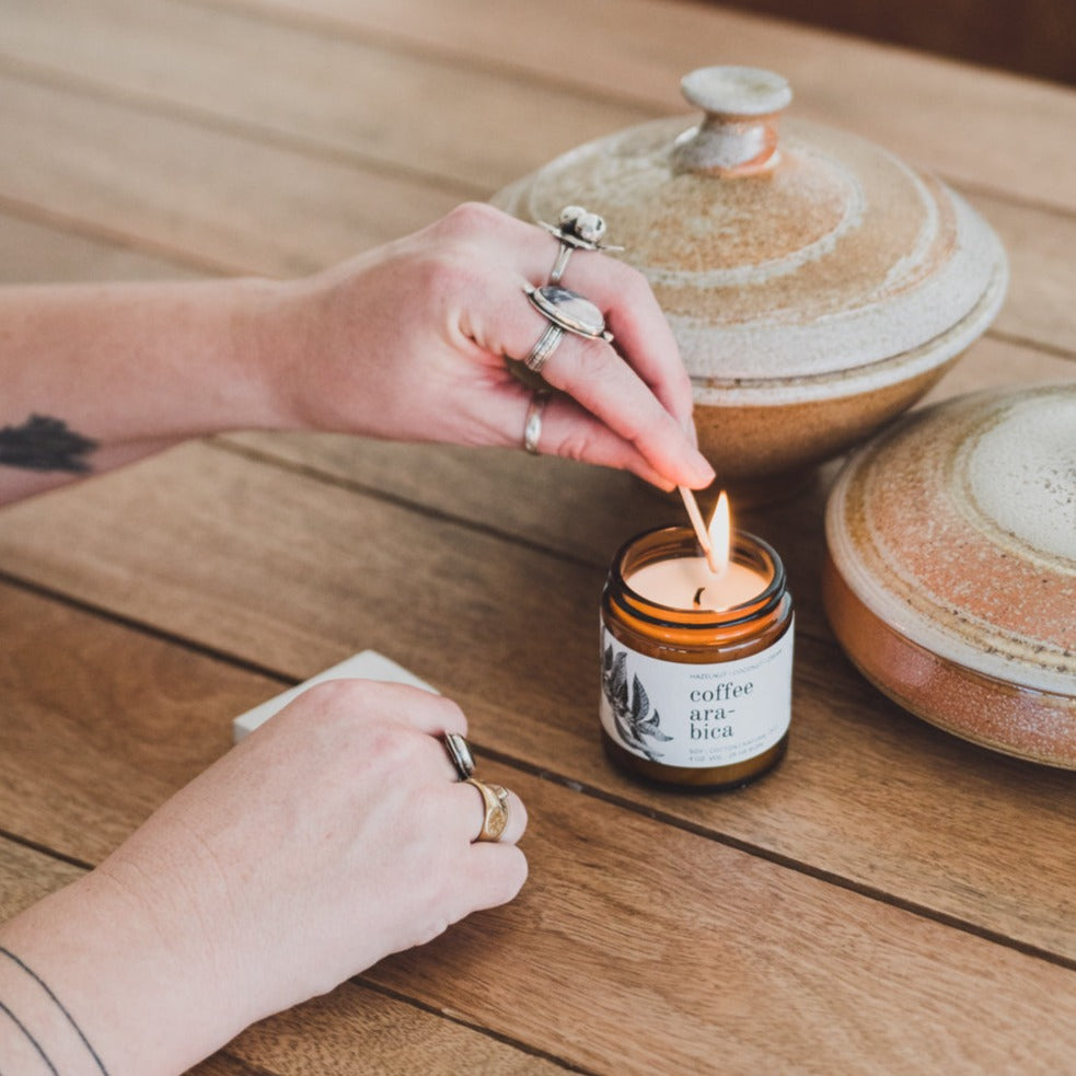 4oz Coconut Sandalwood Soy Candle being lit by a match. 