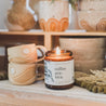 9oz Coffee Arabica Soy Candle on a shelf next to ceramic coffee mugs. 