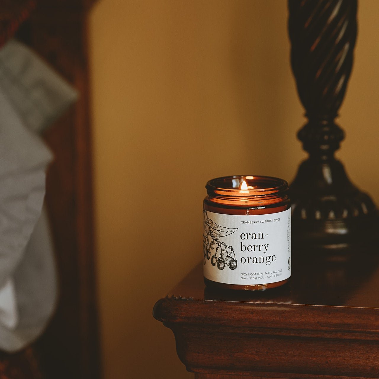 9oz Cranberry Orange Soy Candle on wooden side table. 