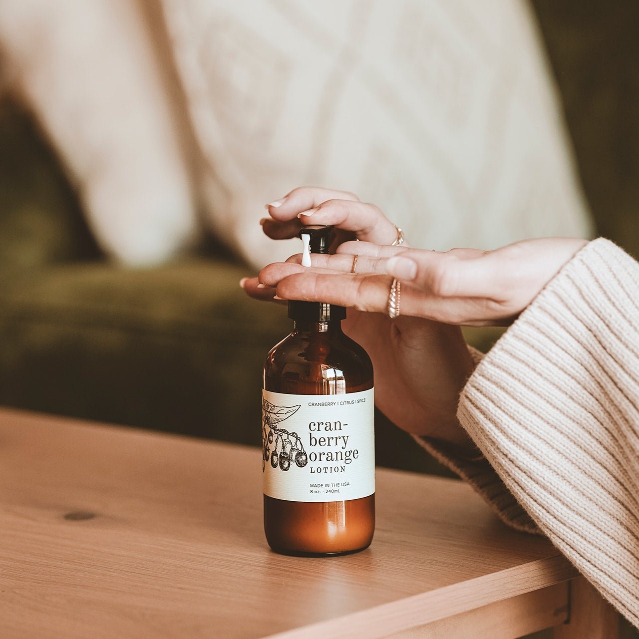 8oz Cranberry Orange Body Lotion being dispensed into a woman's hands. 