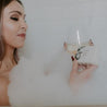 Fresh Squeezed Bar Soap being held by a woman sipping wine in a bathtub. 
