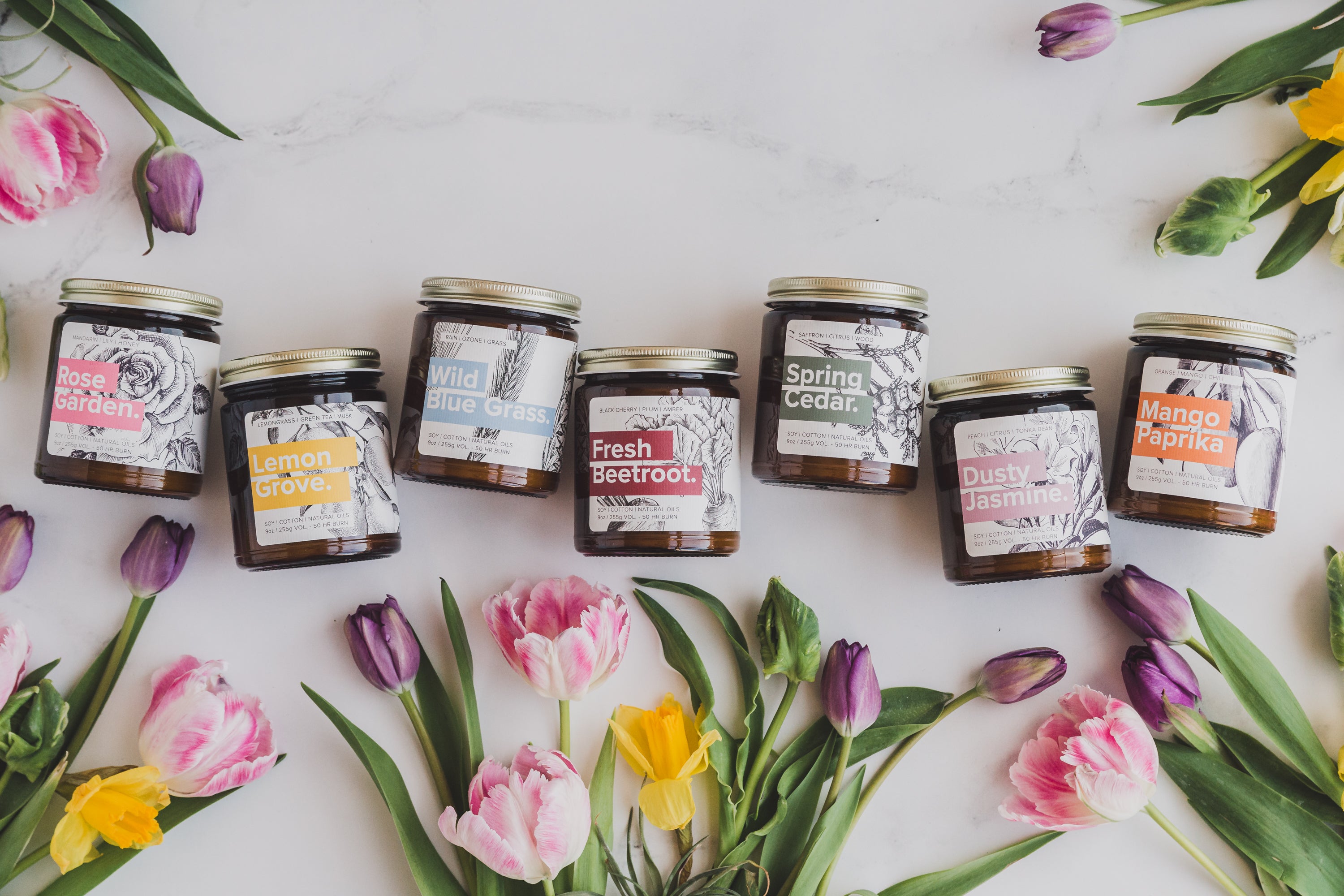 Garden Botanical Soy Candle collection laid out amongst fresh flowers. 