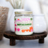 'Ain't No Hood Like Motherhood' 9oz Soy Candle on a decorative wood stand. 