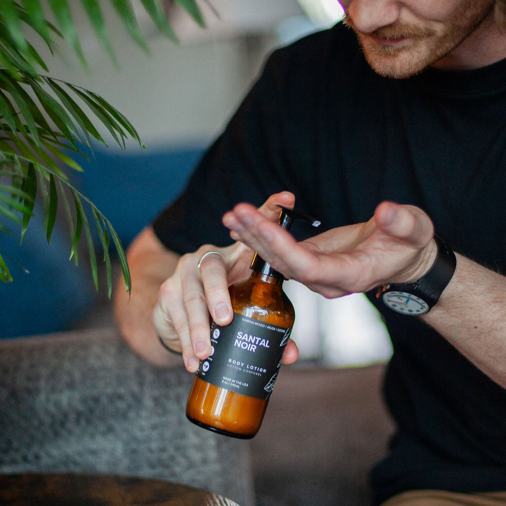 8oz Santal Noir Body Lotion being dispensed into men's hands. 