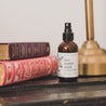 4oz Lavender Mint Linen Spray next to two books.