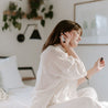 Mount Bachelor Roll-On Perfume being applied by a woman sitting on a bed. 