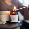 9oz Nordic Orchard Soy Candle being lit by a long match. 