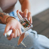 Woman spraying Paradise Perfume on wrist. 