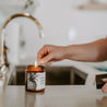 9oz Pineapple Sage Soy Candle being lit by a match. 