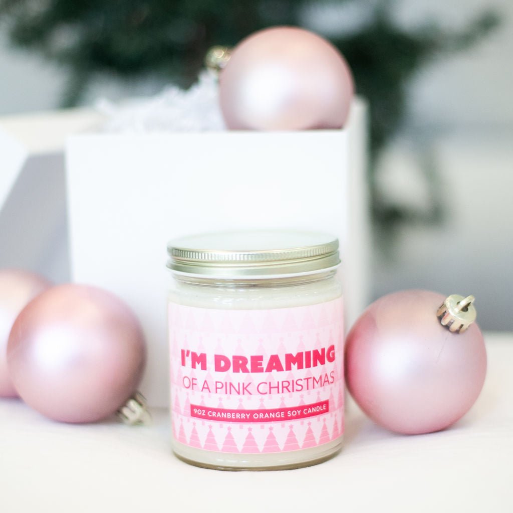 'I'm Dreaming of a Pink Christmas' 9oz Soy Candle next to pink Christmas tree ornaments. 