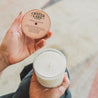 11oz French 75 Soy Candle being held in one hand with a French 75 cocktail recipe being held in the other hand.  