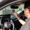 Santal Noir Car Freshener hanging from a rear view mirror with a man reaching for it. 
